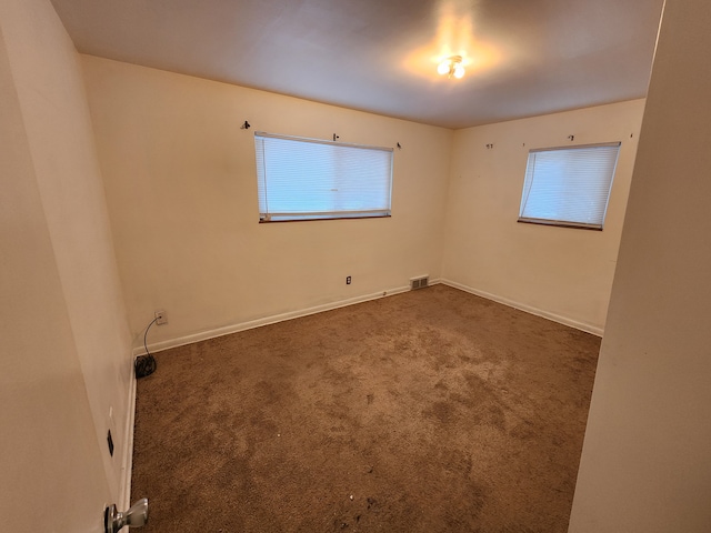 carpeted spare room featuring visible vents, baseboards, and a healthy amount of sunlight