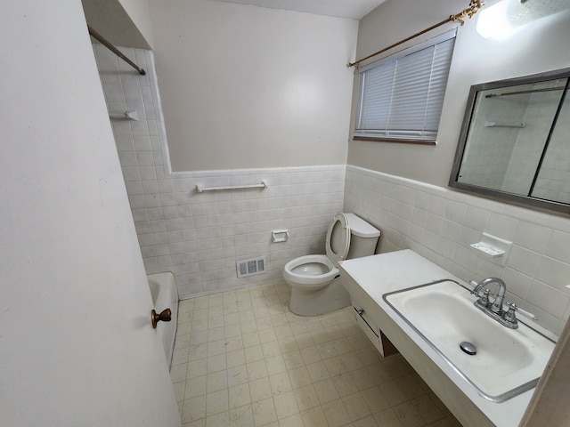 bathroom featuring visible vents, tile walls, a wainscoted wall, toilet, and vanity