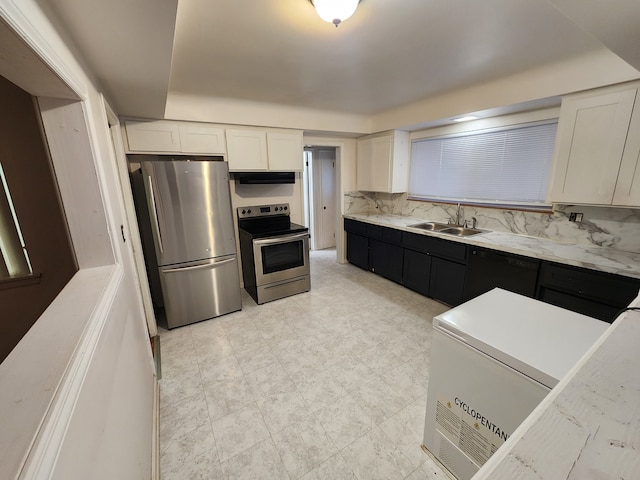 kitchen featuring dark cabinetry, a sink, decorative backsplash, stainless steel appliances, and white cabinetry