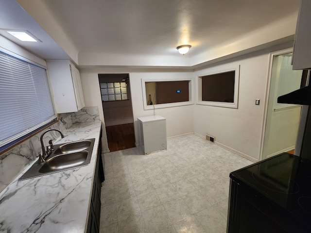 kitchen with tasteful backsplash, visible vents, black range with electric stovetop, fridge, and a sink