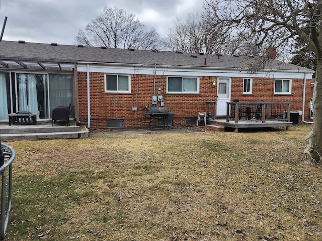 rear view of property with brick siding, a lawn, cooling unit, a deck, and a patio area