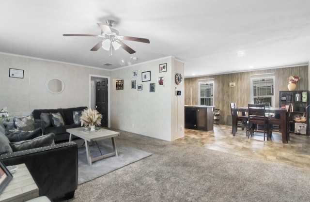 carpeted living room with ornamental molding and ceiling fan