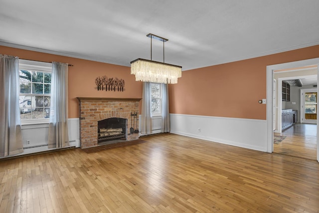 unfurnished living room with crown molding, a baseboard radiator, wood-type flooring, and a brick fireplace