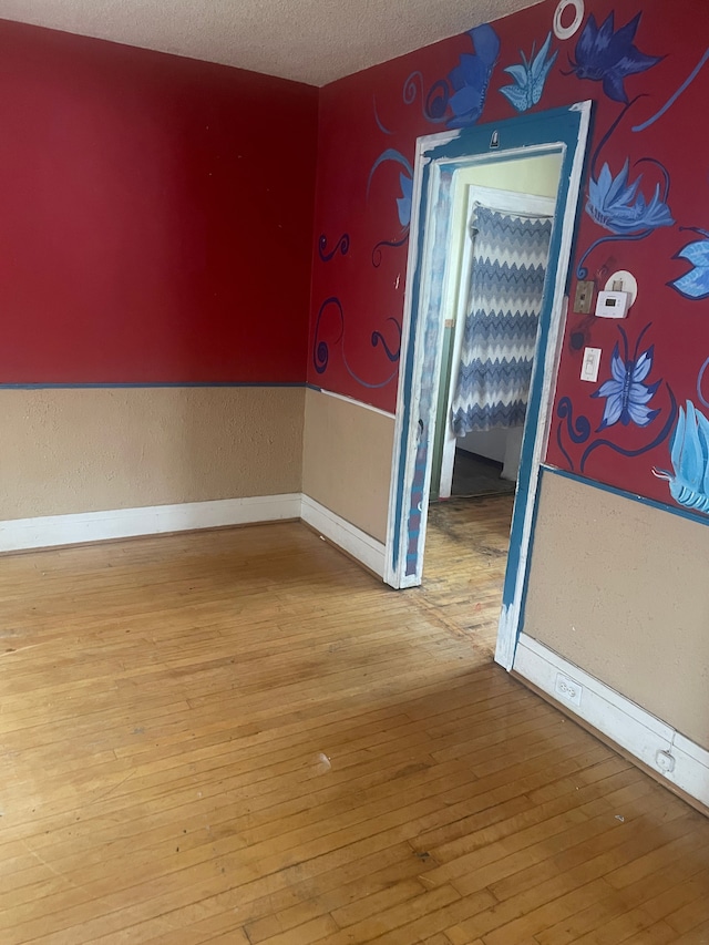 empty room with hardwood / wood-style flooring and a textured ceiling