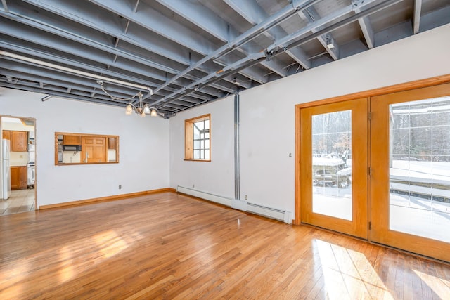 interior space featuring baseboard heating, white fridge, light hardwood / wood-style floors, and a notable chandelier