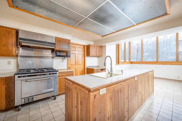 kitchen featuring light tile patterned floors, extractor fan, high end range, sink, and a kitchen island with sink