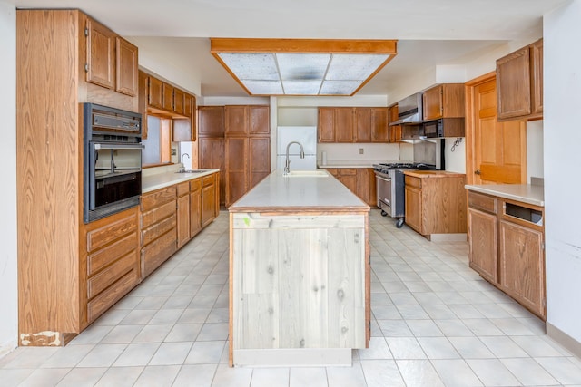 kitchen featuring sink, a center island with sink, oven, and gas stove