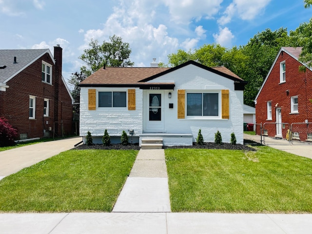 view of front of house with brick siding, fence, and a front yard