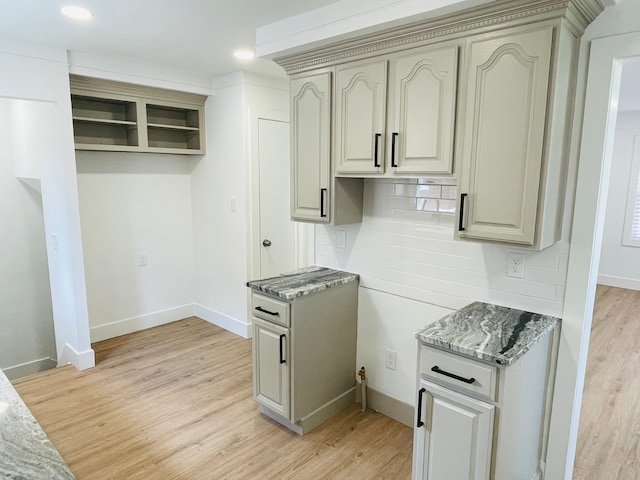 kitchen with light wood finished floors, tasteful backsplash, light stone counters, and baseboards