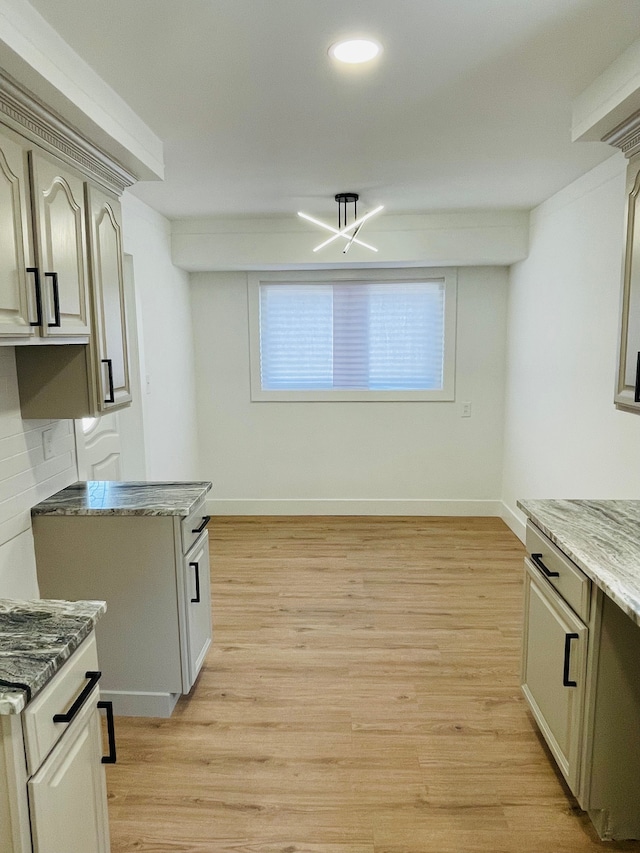 kitchen featuring light wood-style floors, baseboards, and dark stone counters