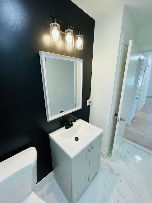 bathroom featuring marble finish floor, vanity, toilet, and baseboards