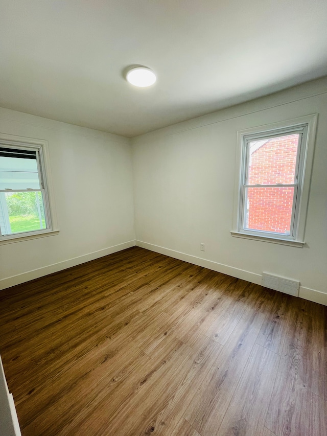 spare room with light wood-style floors, visible vents, and baseboards