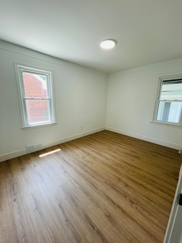 unfurnished room with light wood-type flooring, visible vents, and baseboards