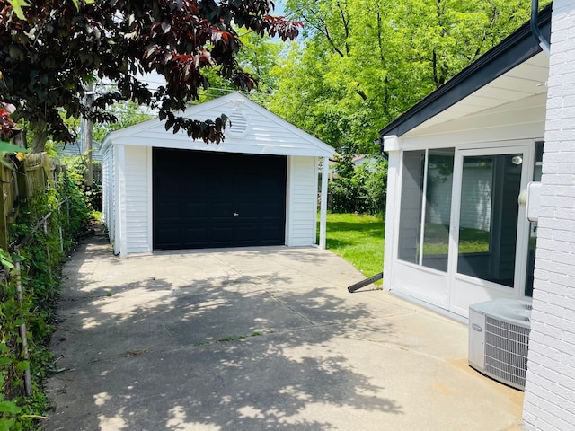 detached garage featuring fence, cooling unit, and concrete driveway