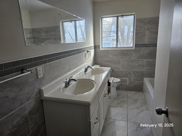 bathroom featuring vanity, toilet, tile walls, and a wealth of natural light