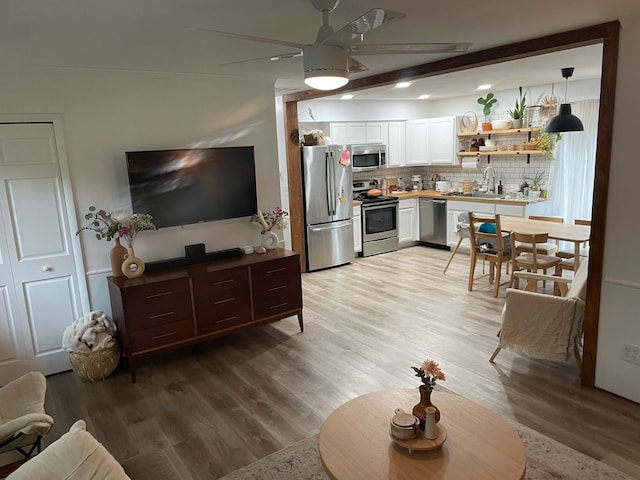 living room with ceiling fan, beam ceiling, light hardwood / wood-style floors, and sink