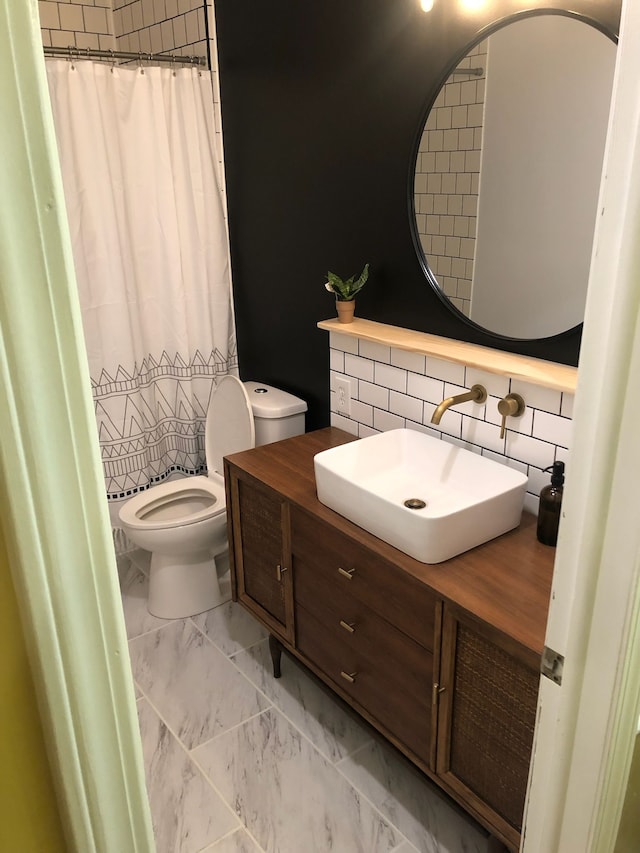 bathroom featuring vanity, backsplash, toilet, and walk in shower