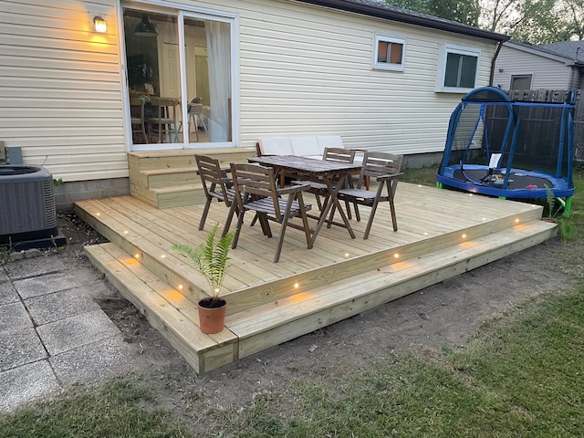 wooden deck featuring a trampoline and central air condition unit