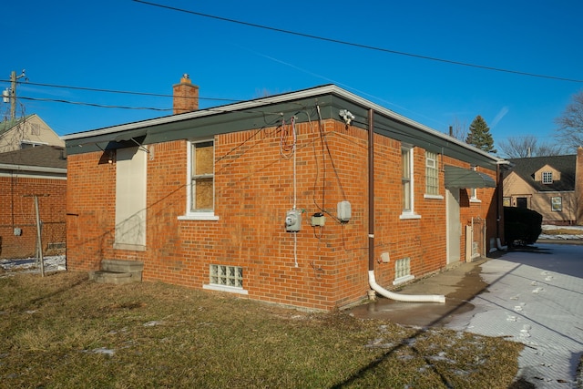 8679 Burt Rd, Detroit, MI 48228 - view of home's exterior with brick siding, a chimney, and a lawn