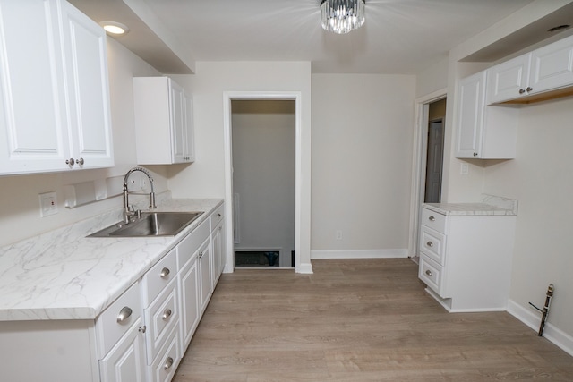 8679 Burt Rd, Detroit, MI 48228 - kitchen featuring a sink, white cabinets, light wood-style floors, and baseboards