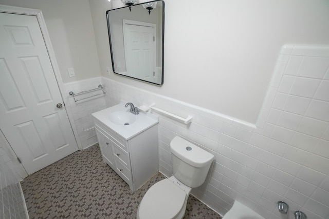 bathroom with tile walls, vanity, tile patterned flooring, and toilet