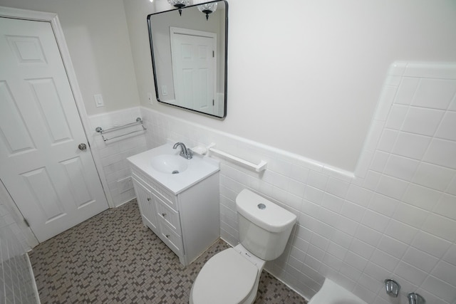 8679 Burt Rd, Detroit, MI 48228 - bathroom with a wainscoted wall, vanity, toilet, tile walls, and tile patterned floors