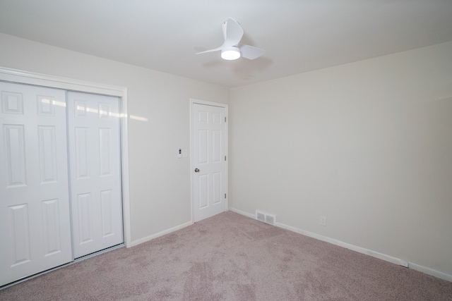 unfurnished bedroom with light carpet, ceiling fan, and a closet