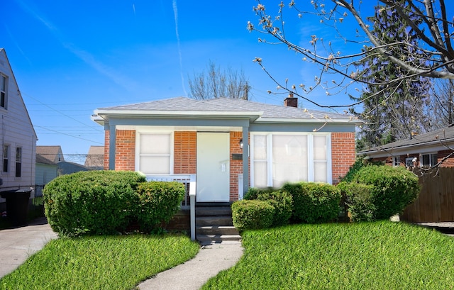 8679 Burt Rd, Detroit, MI 48228 - bungalow-style house featuring brick siding, a chimney, a front lawn, and roof with shingles