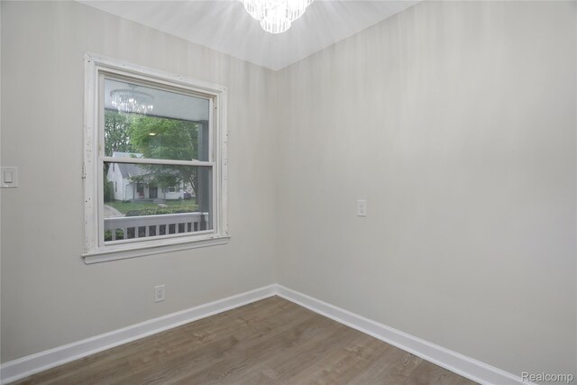 8679 Burt Rd, Detroit, MI 48228 - unfurnished room with a chandelier, baseboards, and wood finished floors
