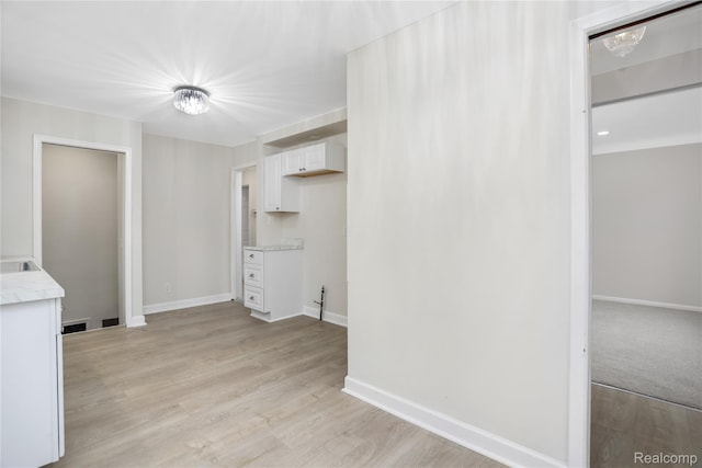 8679 Burt Rd, Detroit, MI 48228 - kitchen with white cabinets, light countertops, baseboards, and light wood-style flooring