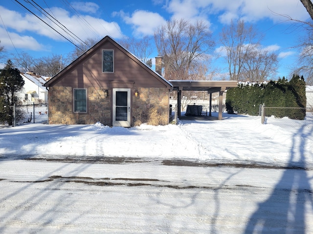 view of front of home featuring stone siding, a chimney, and fence