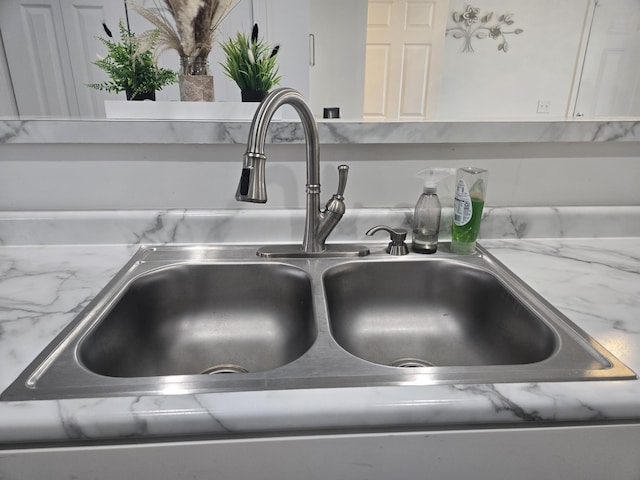 interior details featuring light stone counters, sink, and white cabinetry