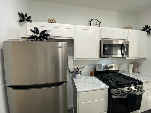 kitchen featuring light stone counters, stainless steel appliances, and white cabinets