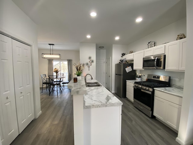 kitchen featuring appliances with stainless steel finishes, decorative light fixtures, sink, and white cabinets