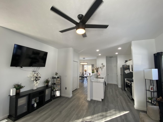 living room with ceiling fan, sink, a textured ceiling, and dark hardwood / wood-style flooring