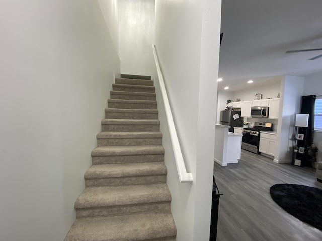 stairs with ceiling fan and hardwood / wood-style floors