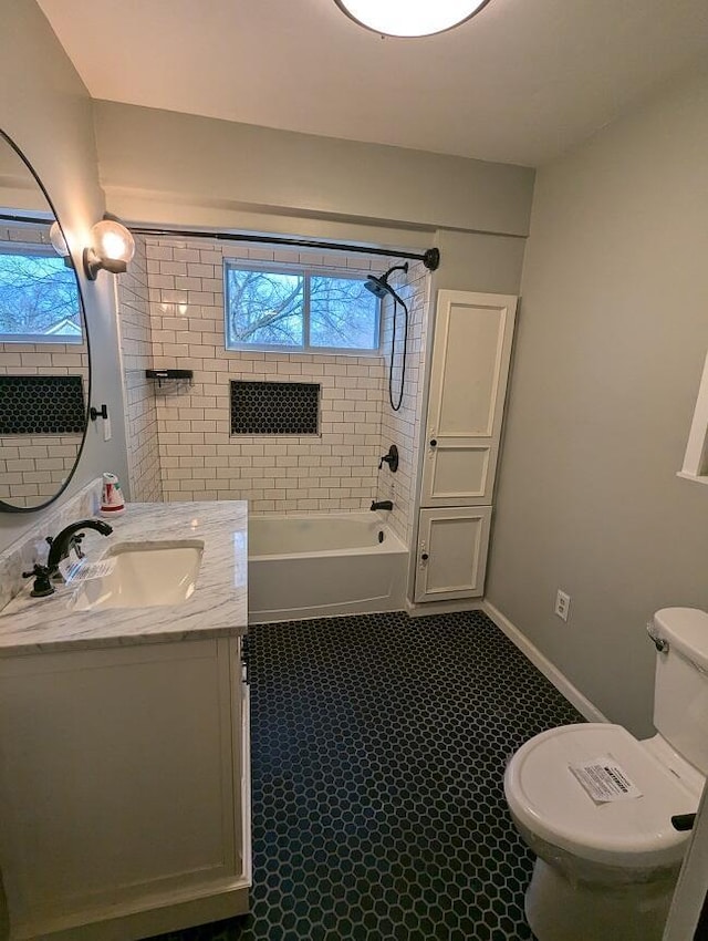 full bathroom with tiled shower / bath, vanity, toilet, and a wealth of natural light