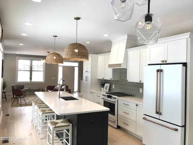 kitchen featuring white cabinetry, high end appliances, sink, and an island with sink