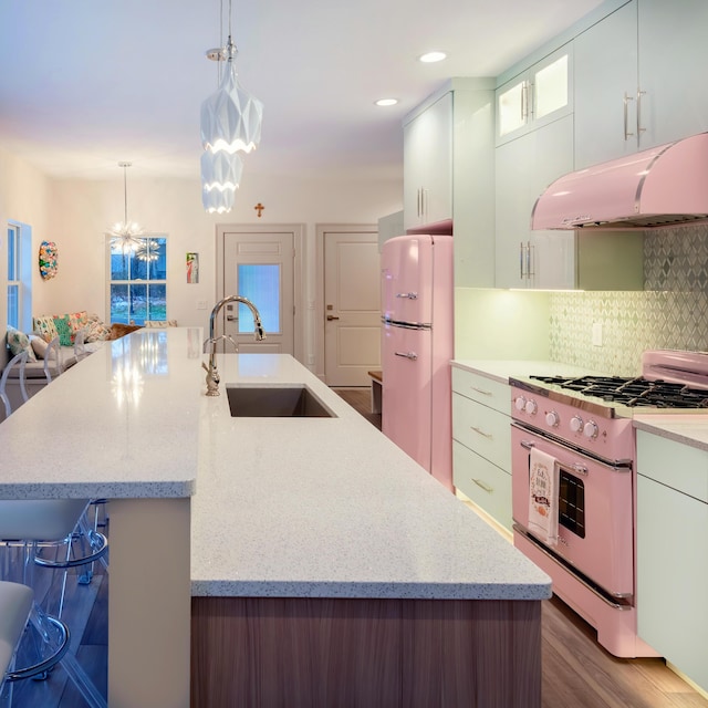 kitchen with sink, decorative light fixtures, fridge, stove, and white cabinets