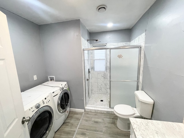 bathroom featuring an enclosed shower, vanity, toilet, and washing machine and clothes dryer