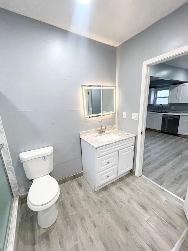 bathroom featuring wood-type flooring, a shower with shower door, vanity, and toilet