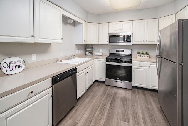 kitchen with white cabinetry, appliances with stainless steel finishes, sink, and wood-type flooring