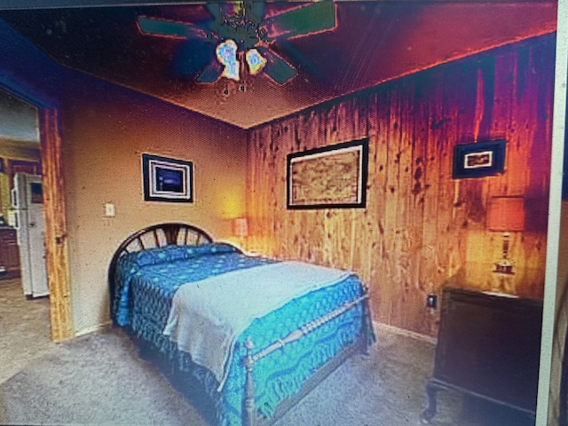 carpeted bedroom with wooden walls and ceiling fan