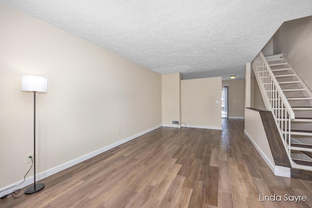 unfurnished living room with wood-type flooring and a textured ceiling