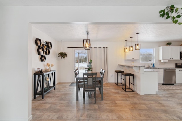 dining area featuring sink, a textured ceiling, and light hardwood / wood-style floors