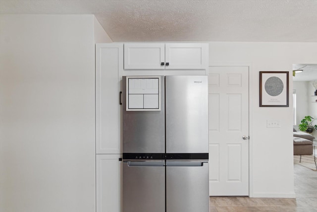 kitchen with white cabinetry, stainless steel fridge, and a textured ceiling