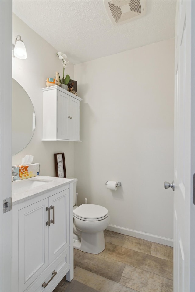 bathroom with vanity, hardwood / wood-style floors, a textured ceiling, and toilet