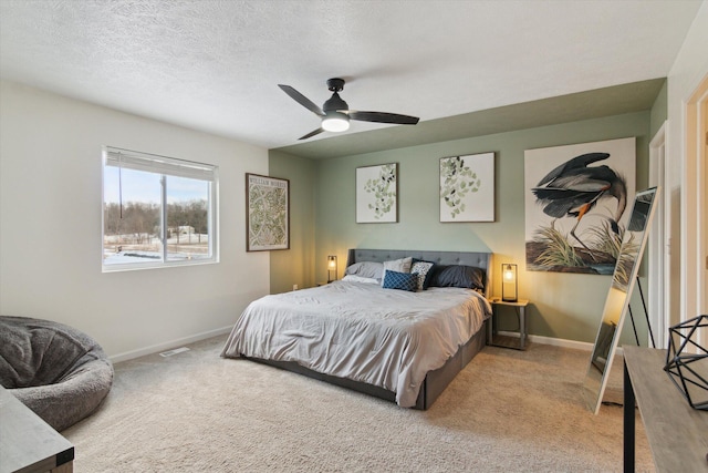 carpeted bedroom featuring ceiling fan and a textured ceiling