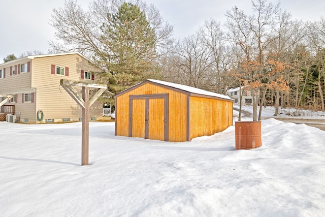 yard layered in snow featuring a shed and central air condition unit