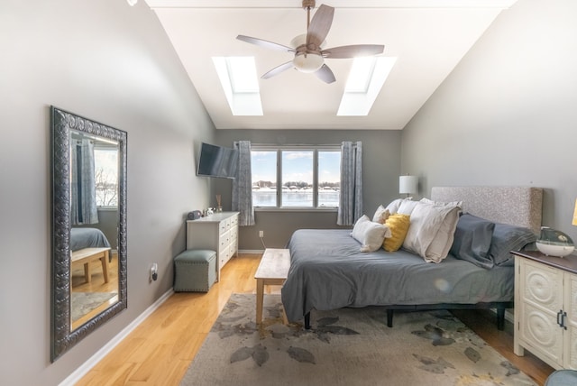 bedroom with lofted ceiling with skylight, light hardwood / wood-style floors, and multiple windows